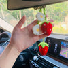 Une main tient un pendentif de clé en crochet de fraise fait main avec des fleurs blanches, accroché dans l'intérieur d'une v