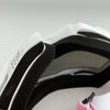 Close-up view of white and black off-road motorcycle goggles with pink accents