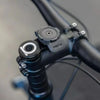 A close-up view of a black universal motorcycle phone mount with a push mechanism.