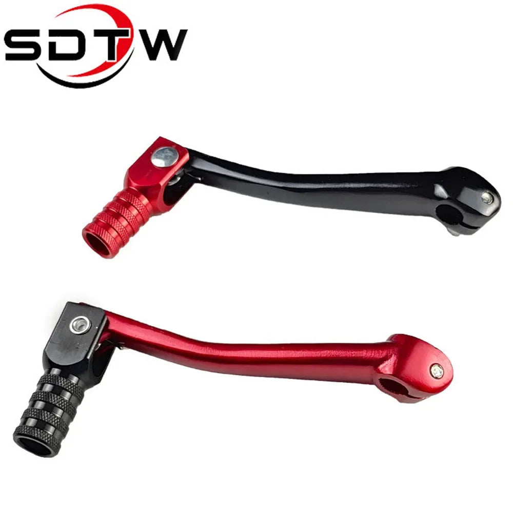 A close-up view of a red motorcycle gear shift lever with a textured grip and black shaft.