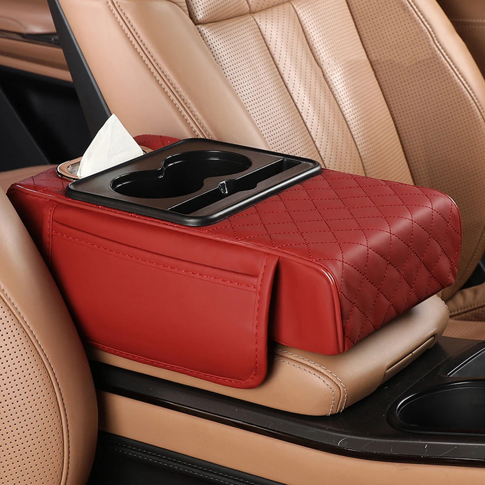 A red quilted car armrest cushion with a tissue holder is placed on a tan leather car seat.