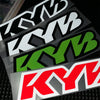 A close-up of three motorcycle decals featuring the KYB logo in black, white, and green colors.
