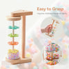 A wooden rainmaker musical toy showing various colored plastic raindrops stacked in a clear tube.