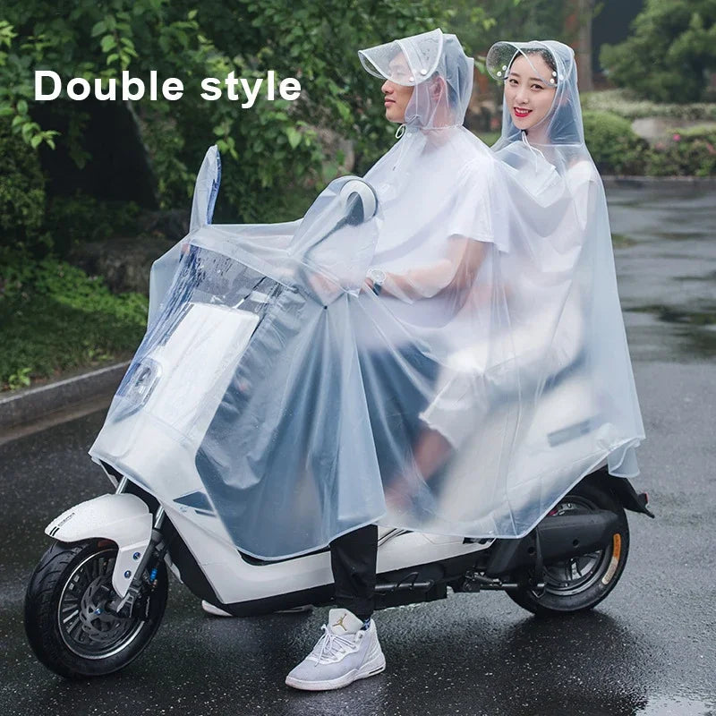 A woman wearing a transparent windproof motorcycle rain poncho sits on a white scooter outdoors.