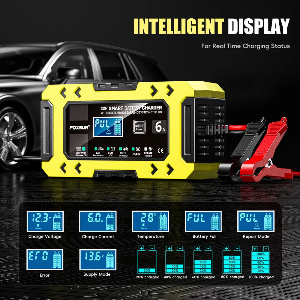 A yellow portable 12V smart battery charger device with a display and red clamp is shown on a dark surface.