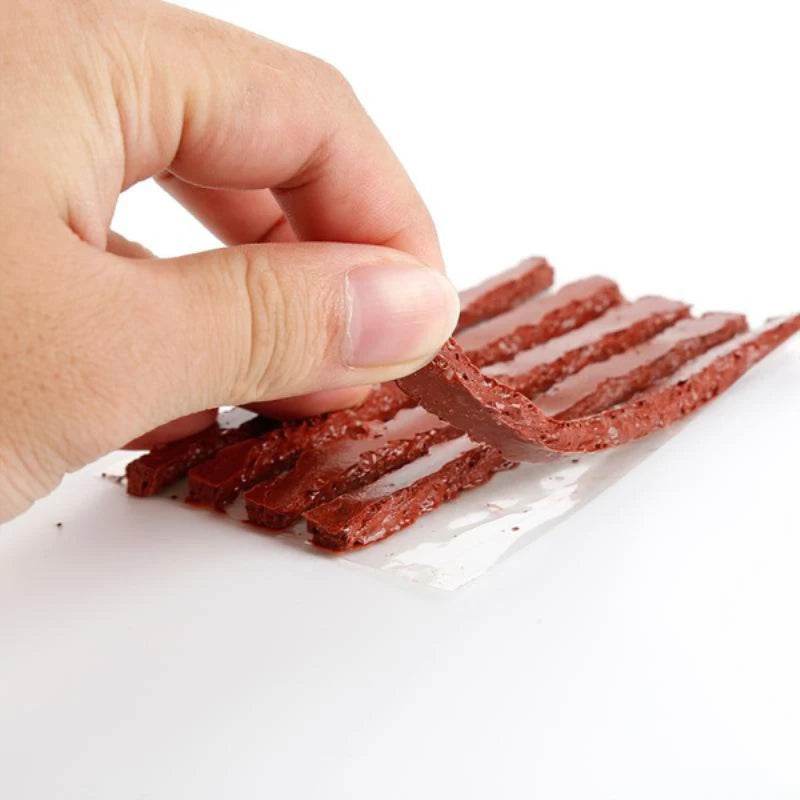 A hand is holding and separating reddish-brown natural rubber tire repair strips on a white surface.