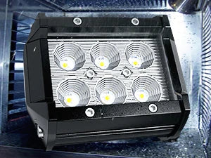 Barre lumineuse LED noire avec quatre sources lumineuses circulaires intenses montées sur une surface métallique.