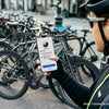 A person holds a smartphone attached to a bike, demonstrating a phone holder for motorcycle safety.