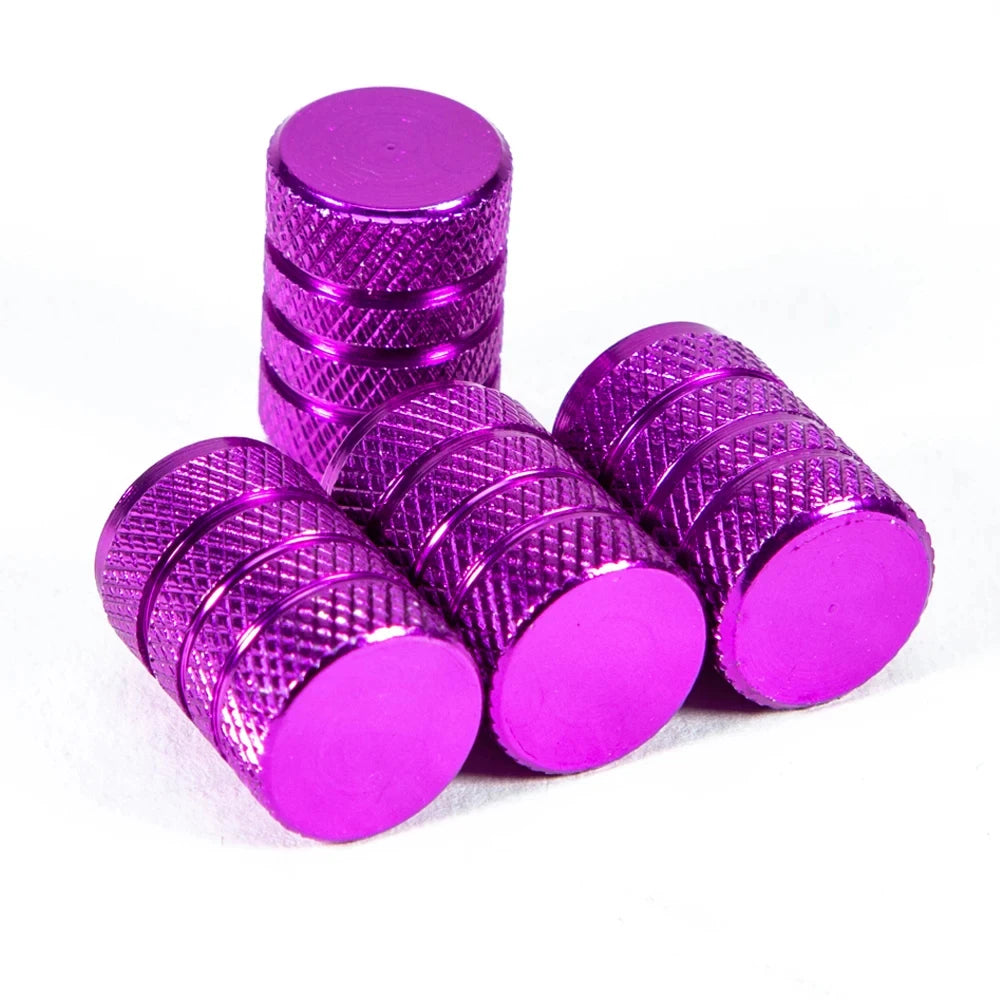 A set of metallic purple aluminum tire valve caps stacked and scattered on a white background.