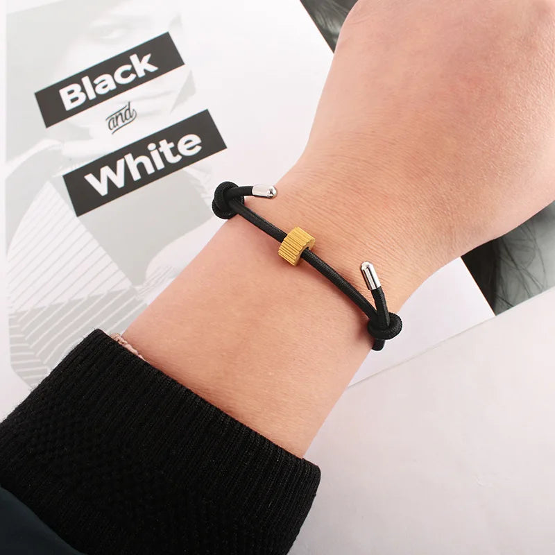 A close-up of a hand wearing a black heart-shaped fitness tracker bracelet on a wrist.
