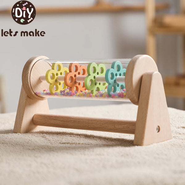 A wooden rainmaker musical toy featuring colorful, interlocking plastic raindrops displayed in a wooden frame.