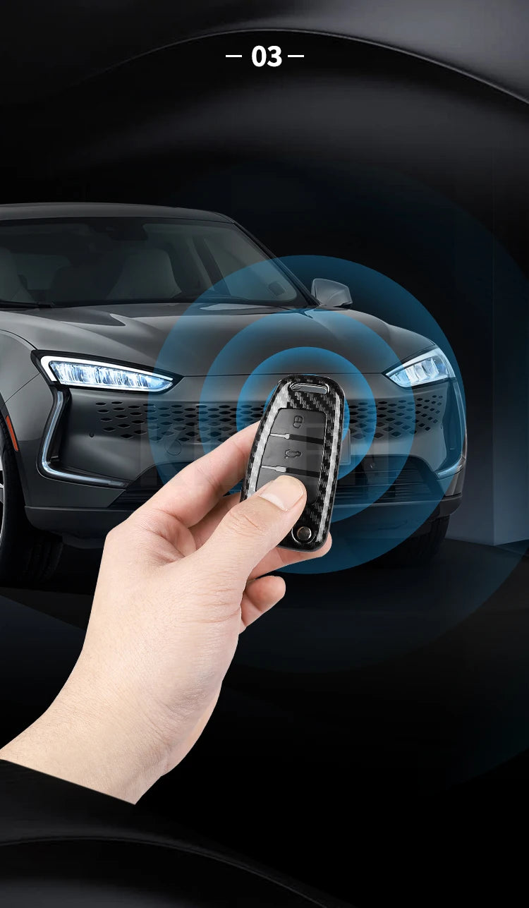 A hand holds a carbon fiber car key case cover near a modern car's headlight.
