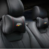 Black PU leather car headrest pillow seatbelt shoulder pad with red stitching visible in a car interior.