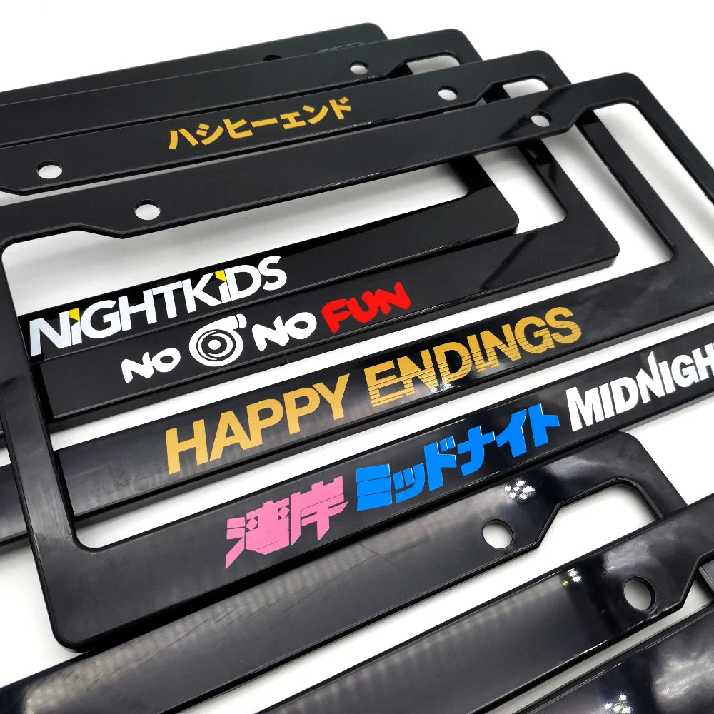 A collection of black JDM racing style license plate frame decorations with various text and designs.