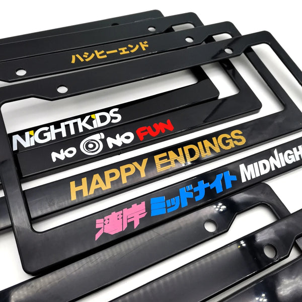 A collection of black JDM racing style license plate frame decorations with various text and designs.