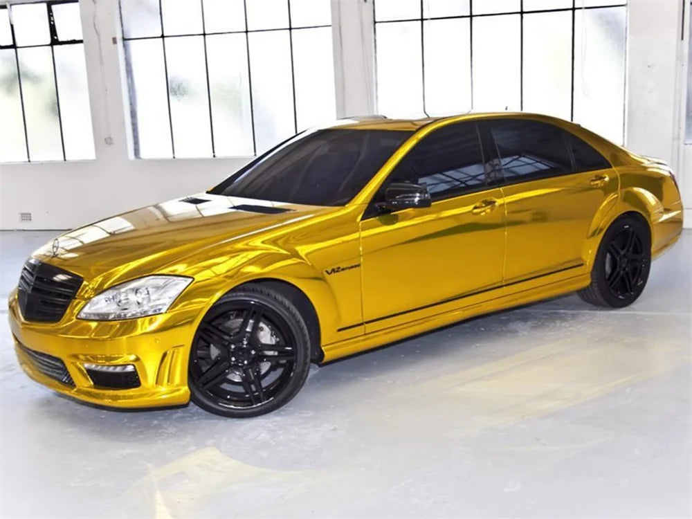 A gold sedan with black wheels parked indoors near large windows.