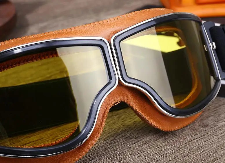 A pair of retro folding motorcycle windproof glasses with brown leather frames and amber tinted lenses.