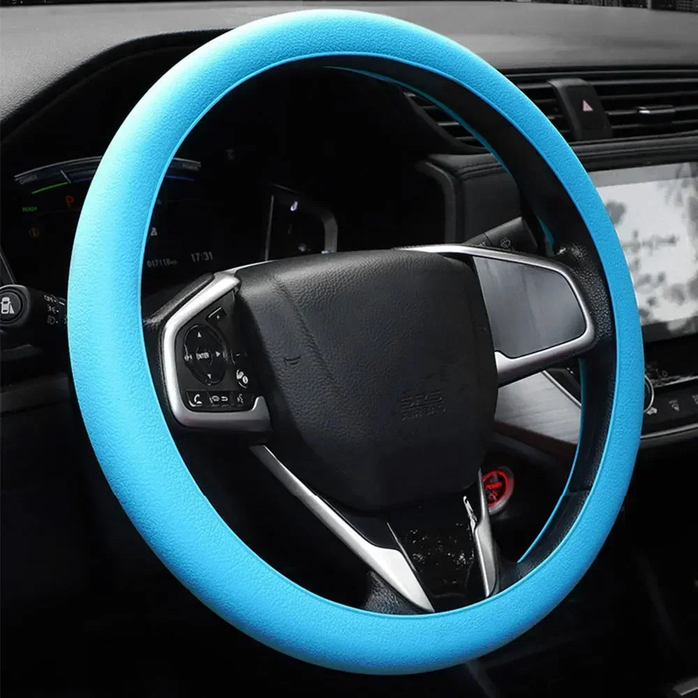 A close-up view of a black steering wheel with a bright blue silicone cover installed.