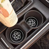 A set of two black silicone car cup coasters is shown inside a dark car compartment.