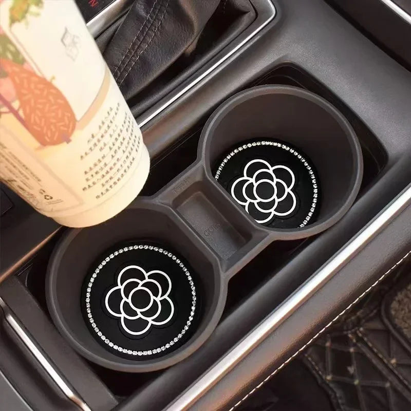 A set of two black silicone car cup coasters is shown inside a dark car compartment.