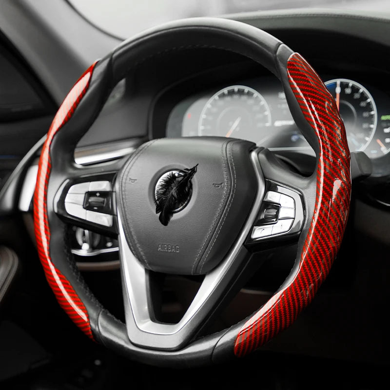 Gros plan d'un volant noir recouvert de protections en fibre de carbone rouge.