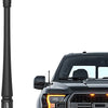 A black universal car antenna is shown next to a black pickup truck grille.
