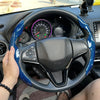 A black steering wheel with a blue and black patterned booster cover installed in a car interior.