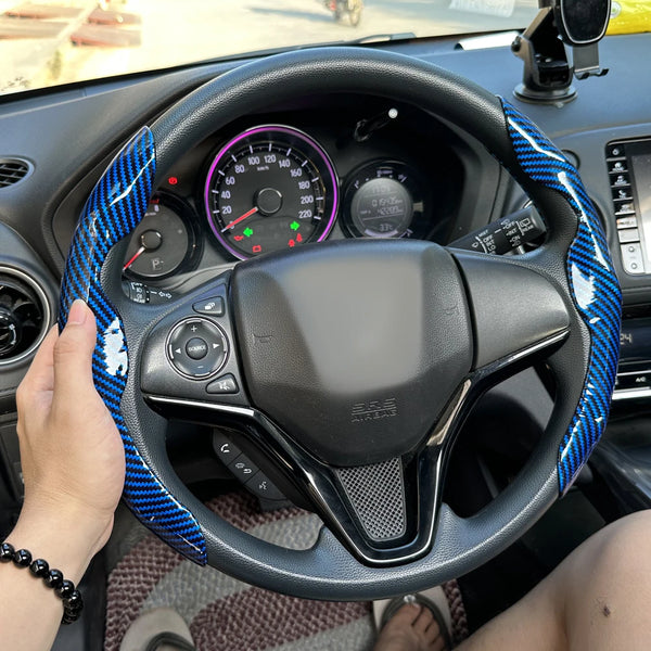 A black steering wheel with a blue and black patterned booster cover installed in a car interior.