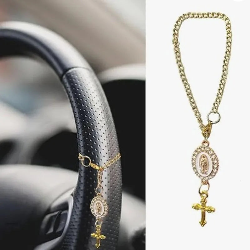 A gold chain necklace with a pendant featuring a religious figure is displayed next to a car steering wheel.