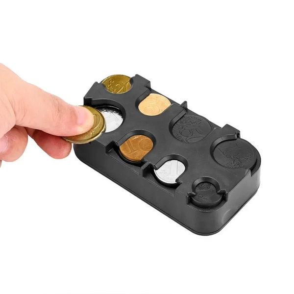 A hand holds a black multi-currency coin storage box with several gold and silver coins inside.