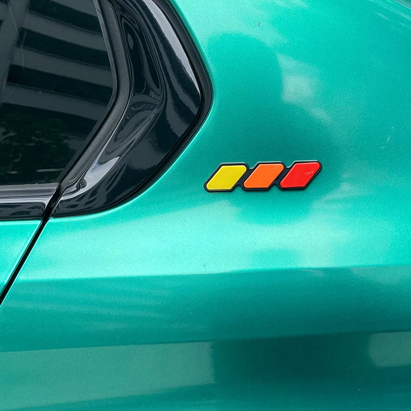 Close-up of a teal car body featuring an orange, yellow, and red tri-color decal on the side panel.