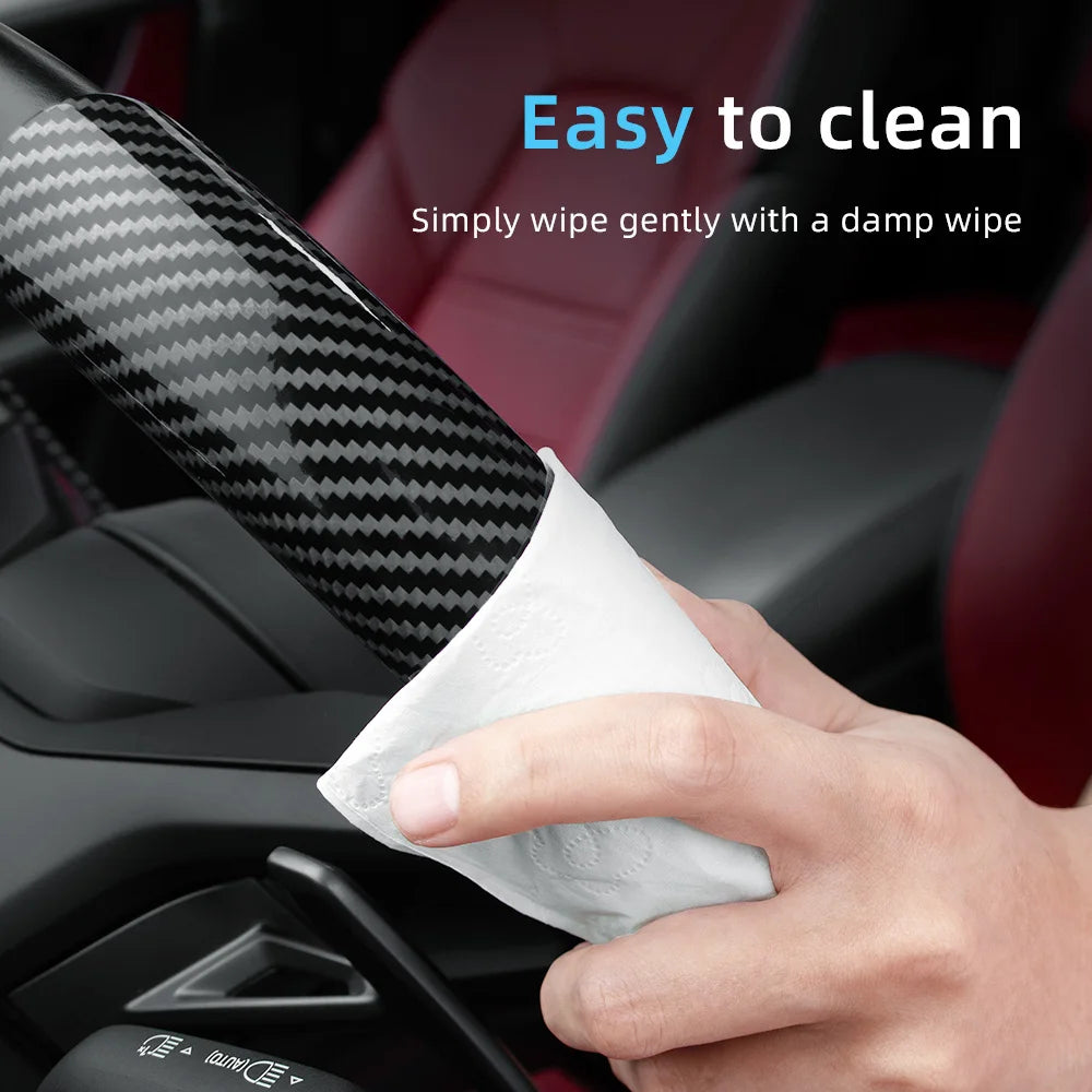 A hand is wiping a carbon fiber texture steering wheel cover with a damp wipe for easy cleaning.