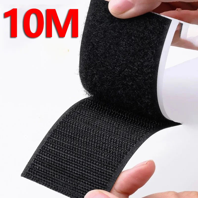 Black hook and loop tape strips being held by a hand, showing the texture and size of the material.