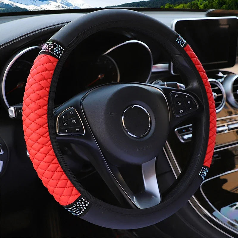Close-up of a black steering wheel with an orange embroidered leather cover and silver accents.