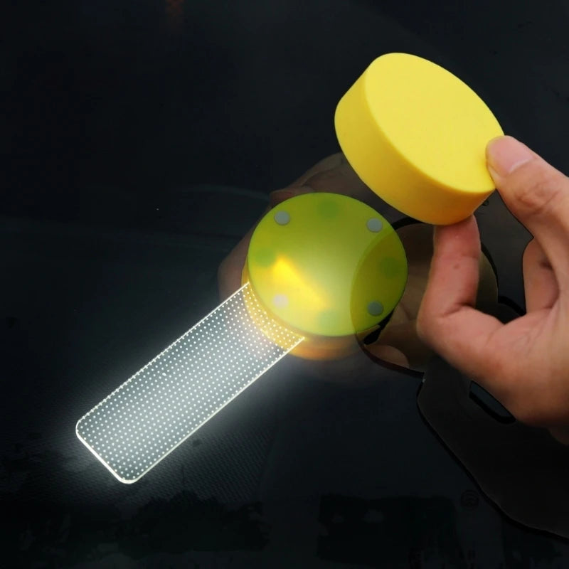 Eine Hand hält ein gelbes magnetisches Folien-Scher-Licht, das ein Gittermuster auf einer dunklen Oberfläche beleuchtet.