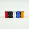 A set of eight aluminum tire valve caps in red, black, silver, blue, and orange stacked in a row.
