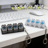 A set of illuminated mechanical keyboard keychains with blue lights displayed on a white desk.