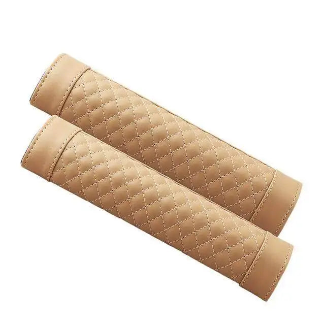 A pair of tan quilted PU leather car seat belt covers rolled up and displayed diagonally.