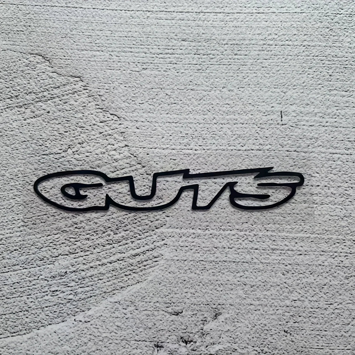 Black stylized text reading GUTS printed on a gray textured surface.