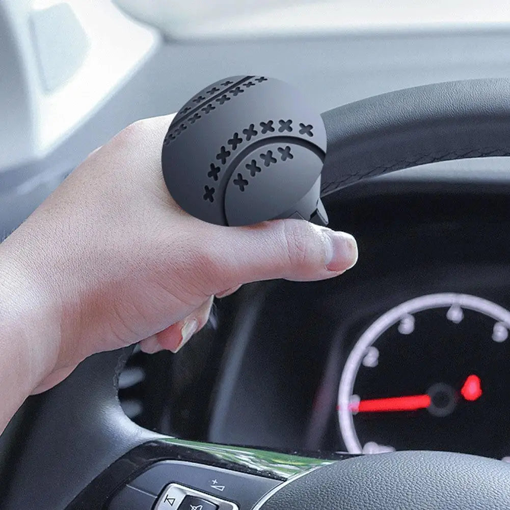 Eine Hand hält ein schwarzes Lenkrad-Booster-Gerät in der Nähe des Lenkrads eines Autos.