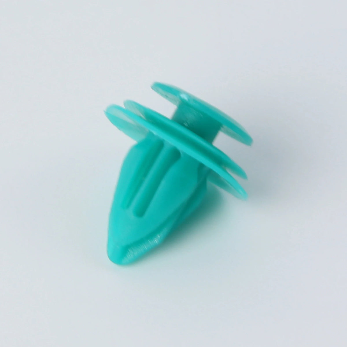 A close-up view of a teal automotive fastener clip used for trim and bumper installation.