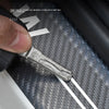 A close-up of a thick, metallic door sill protector resting on a textured black surface.