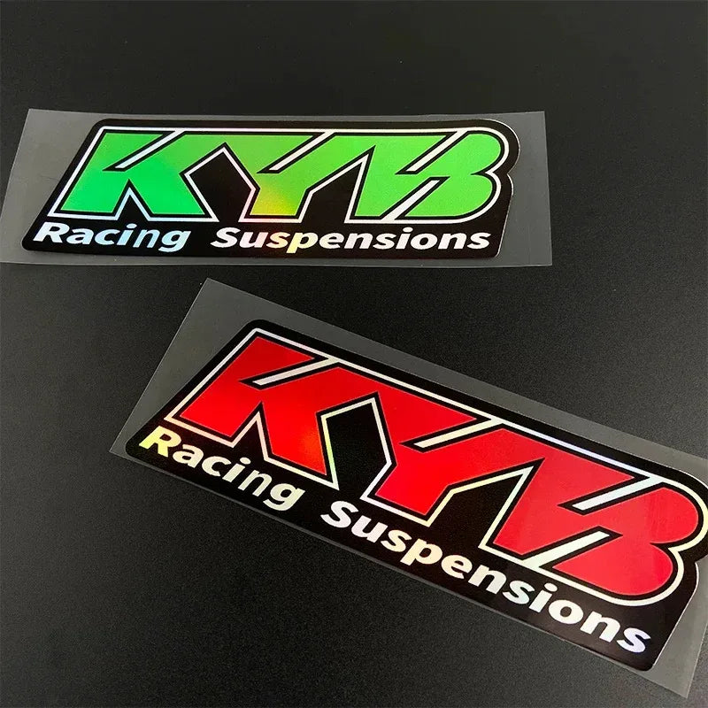 Two rectangular decals featuring the KYB Racing Suspensions logo in green and red on a black background.