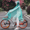 A person wearing a transparent windproof motorcycle rain poncho is riding an orange bicycle on a paved road.
