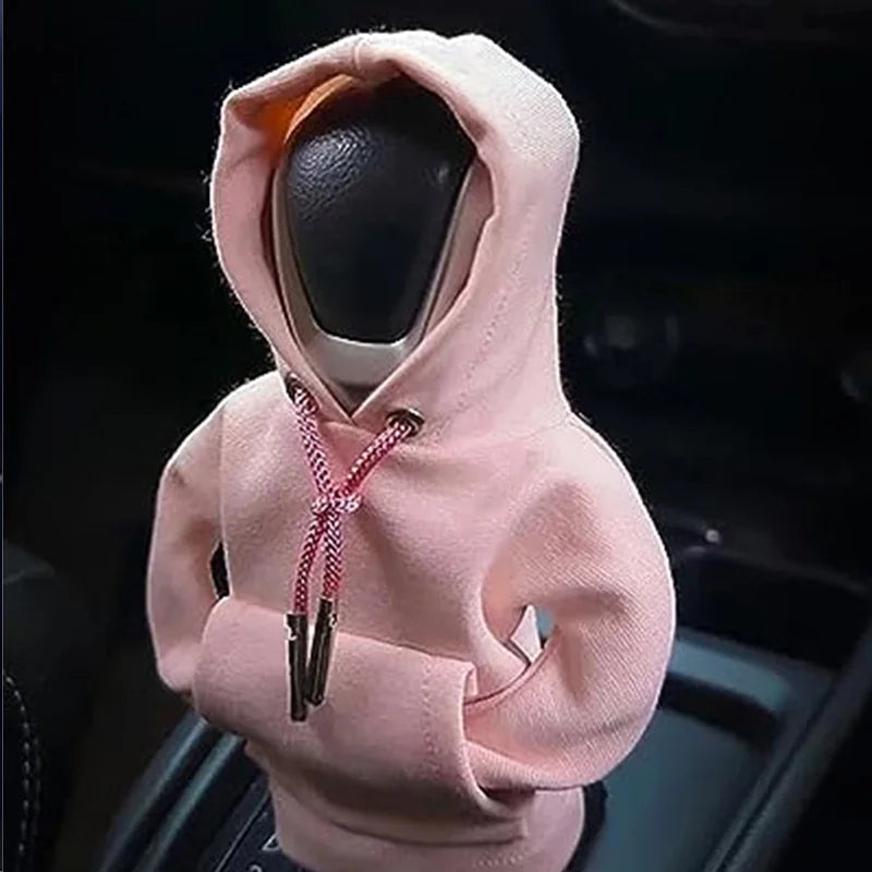 A light pink cozy knit gear shift cover for a manual transmission is shown in a close-up view.