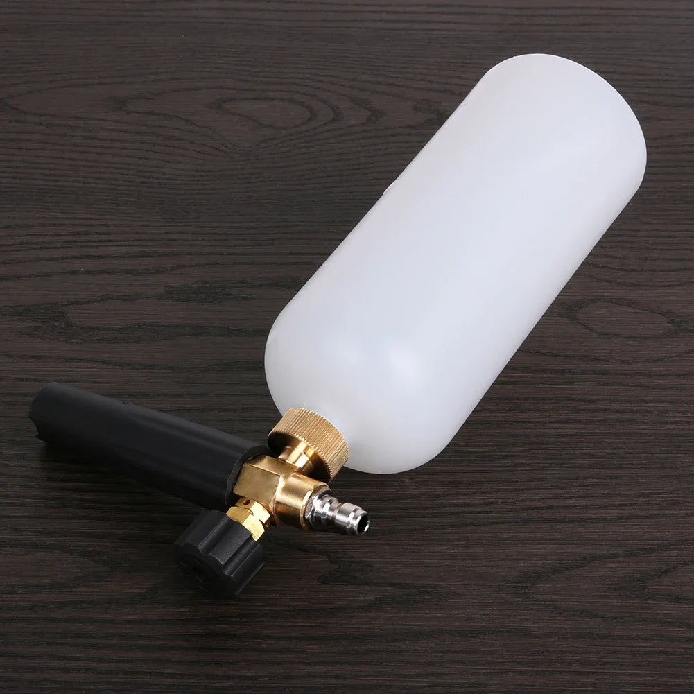 A white high-pressure car cleaning foam gun with a black handle and brass fitting resting on a dark wooden surface.