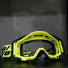 A pair of bright yellow high-performance motocross goggles resting on a dark surface.