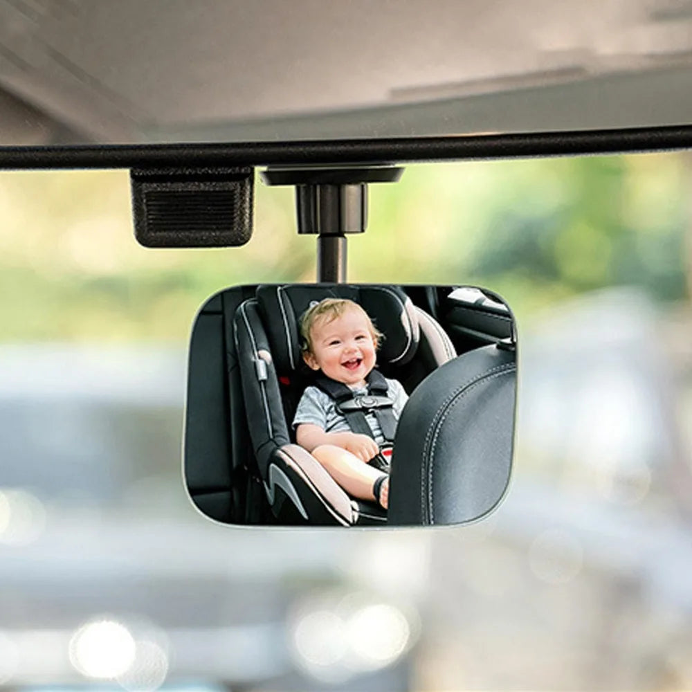 A child is seated in a black car seat within a 360° adjustable HD blind spot mirror for car safety.