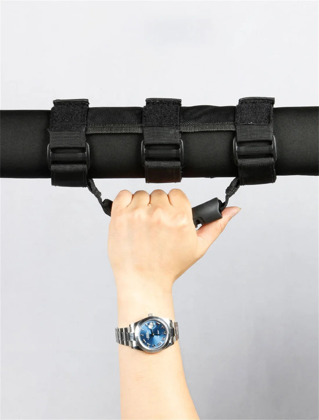 A hand grips a black roll bar grab handle on a vehicle.