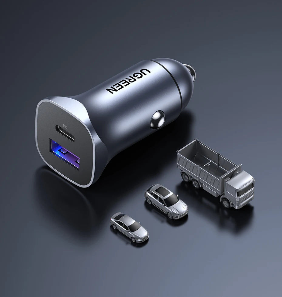 A silver Ugreen 30W dual-port USB-C fast car charger is shown on a dark surface with miniature cars.